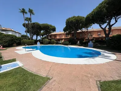 a swimming pool in a yard with trees and a building at Villa Serena in Chiclana de la Frontera
