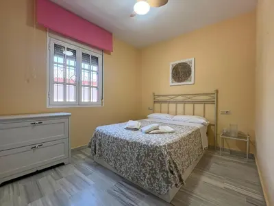 a bedroom with a bed and a dresser and a window at Villa Serena in Chiclana de la Frontera