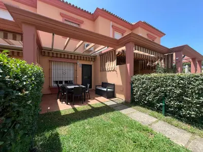 a pink house with a patio with a table and chairs at Villa Serena in Chiclana de la Frontera