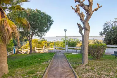 a brick path through a park with trees and the ocean at Brisa del Mar II, Apartamentos Living Sur in Sanlúcar de Barrameda