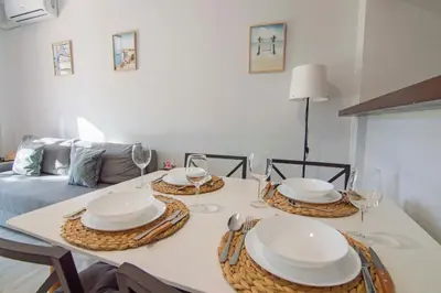 a dining room table with plates and wine glasses at Brisa del Mar II, Apartamentos Living Sur in Sanlúcar de Barrameda