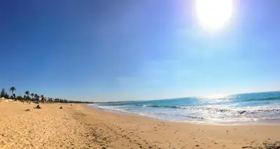 a beach with people sitting on the sand and the ocean at PASSIVE HOUSE in Novo Sancti Petri