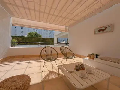 a living room with two chairs and a table at Anc14 Apartamento con 2 habitaciones, patio y piscina al lado de la playa in El Puerto de Santa María