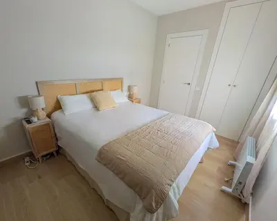 a bedroom with a large bed and a wooden floor at Anc14 Apartamento con 2 habitaciones, patio y piscina al lado de la playa in El Puerto de Santa María
