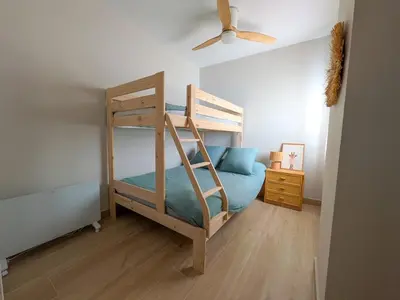 a bedroom with a bunk bed and a ceiling fan at Anc14 Apartamento con 2 habitaciones, patio y piscina al lado de la playa in El Puerto de Santa María