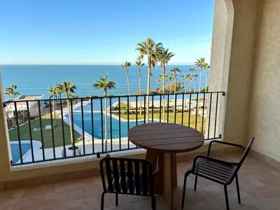 a balcony with a table and chairs and a view of the ocean at Hotel Punta Bermeja Premium in El Puerto de Santa María