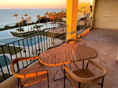 a table and chairs on a balcony with a view of the ocean at Hotel Punta Bermeja Premium in El Puerto de Santa María
