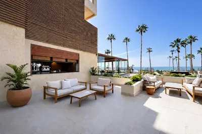 a patio with chairs and tables and palm trees at Hotel Punta Bermeja Premium in El Puerto de Santa María