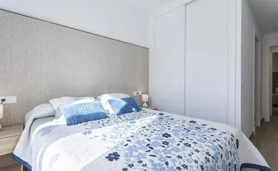 a bedroom with a blue and white bed with blue pillows at Chic & Bright Costa Ballena Getaway in Chipiona