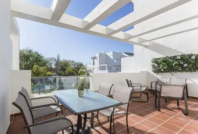a patio with a table and chairs on a balcony at Chic & Bright Costa Ballena Getaway in Chipiona