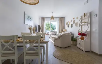 a dining room and living room with a table and chairs at Chic & Bright Costa Ballena Getaway in Chipiona