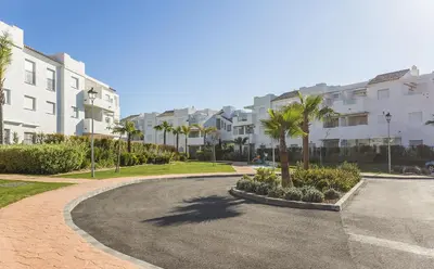 a winding road with palm trees and buildings at Chic & Bright Costa Ballena Getaway in Chipiona