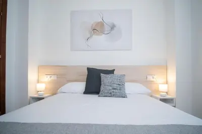 a bedroom with a white bed with two lamps at SIBS Sanlúcar Camelias-Ideal Familias Cerca Playa in Sanlúcar de Barrameda