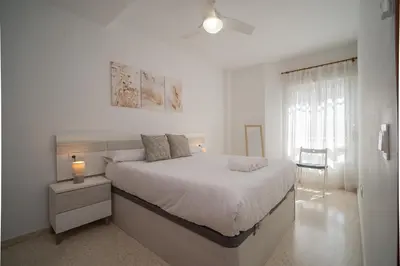 a white bedroom with a large bed and a window at SIBS Sanlúcar Océano-Ideal Familias-Parking y Wifi Gratis in Sanlúcar de Barrameda