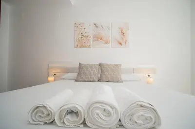 a white bed with three rolled towels on it at SIBS Sanlúcar Océano-Ideal Familias-Parking y Wifi Gratis in Sanlúcar de Barrameda