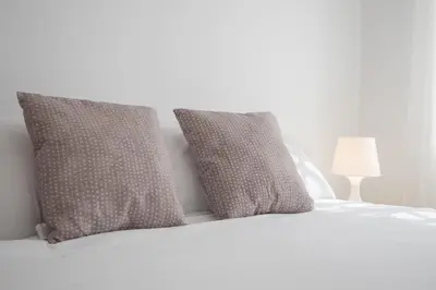 a white bed with two pillows on top of it at SIBS Sanlúcar Océano-Ideal Familias-Parking y Wifi Gratis in Sanlúcar de Barrameda