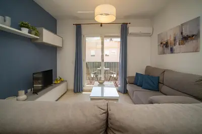 a living room with a couch and a tv at SIBS Sanlúcar Océano-Ideal Familias-Parking y Wifi Gratis in Sanlúcar de Barrameda