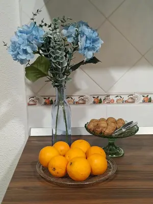 a vase with blue flowers and oranges on a table at El balconcito in Arcos de la Frontera