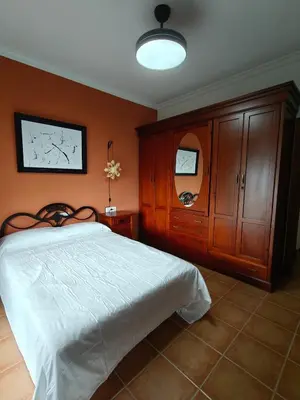 a bedroom with a white bed and wooden cabinets at El balconcito in Arcos de la Frontera