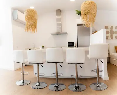 a kitchen with white bar stools in a room at Gallery Vistahermosa in El Puerto de Santa María