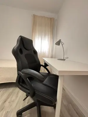 a black chair sitting next to a desk with a lamp at La Joya de Apartamento in Jerez de la Frontera