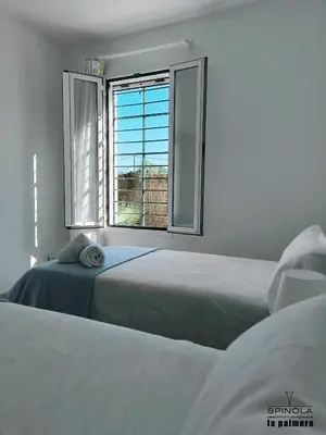 two beds in a white room with a window at Spinola Beachfront Bungalows - Apartamentos bungalow en primera linea de playa en Sanlúcar de Barrameda in Sanlúcar de Barrameda