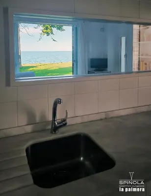 a kitchen sink with a view of the ocean at Spinola Beachfront Bungalows - Apartamentos bungalow en primera linea de playa en Sanlúcar de Barrameda in Sanlúcar de Barrameda