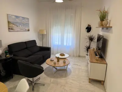 a living room with a black couch and a table at Apartamento Centro Plaza del Cabildo in Sanlúcar de Barrameda