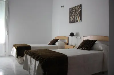 a white room with two beds and a couch at Apartamento Centro Plaza del Cabildo in Sanlúcar de Barrameda
