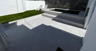 a patio with two white chairs and a pool at Alojamiento rural colarte in Conil de la Frontera