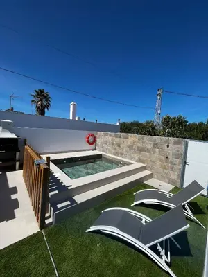 a backyard with a swimming pool and two lawn chairs at Alojamiento rural colarte in Conil de la Frontera