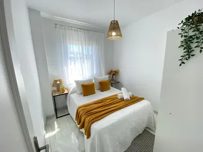 a white bedroom with a bed with yellow pillows at Apartamento Baluarte in Sanlúcar de Barrameda
