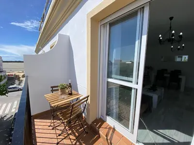 a balcony with a table and a large window at Apartamento Baluarte in Sanlúcar de Barrameda