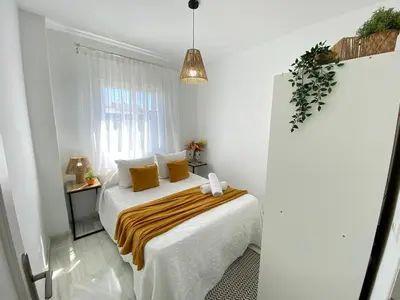 a white bedroom with a bed with yellow pillows at Apartamento Baluarte in Sanlúcar de Barrameda