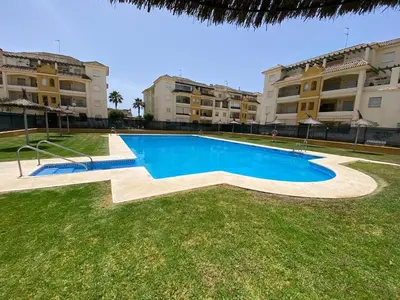 a swimming pool in front of some apartment buildings at Apartamento La Laguna in Chipiona
