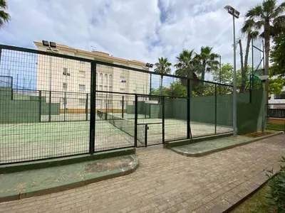 a tennis court with a fence in front of a building at Apartamento La Laguna in Chipiona