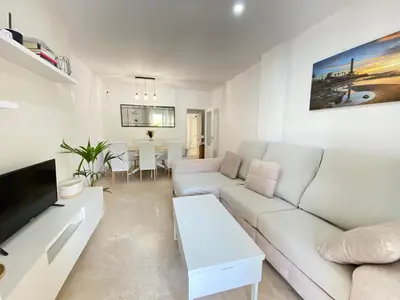 a white living room with a couch and a table at Apartamento La Laguna in Chipiona