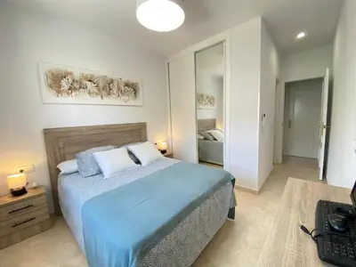 a bedroom with a bed with a blue comforter at Apartamento La Laguna in Chipiona