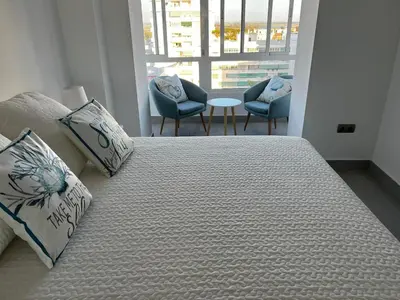 a large bed with pillows and chairs in a room at Apartamento Arena y sal in El Puerto de Santa María