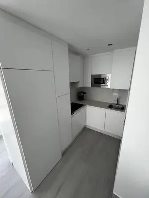 a white kitchen with a sink and a microwave at Apartamento Arena y sal in El Puerto de Santa María