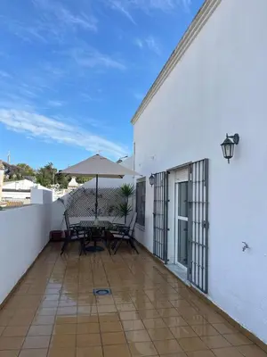 a patio with a table and umbrella on a white building at Ático de Marta, Pleno Centro-Terraza 34m2 in Sanlúcar de Barrameda