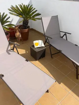 a table and a chair on a floor with plants at Ático de Marta, Pleno Centro-Terraza 34m2 in Sanlúcar de Barrameda