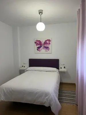 a bedroom with a bed and a pink butterfly painting on the wall at Ático de Marta, Pleno Centro-Terraza 34m2 in Sanlúcar de Barrameda
