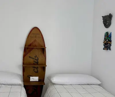 a room with a surfboard on the wall next to two beds at El Vigia Grupo AC Gestion in Vista Hermosa