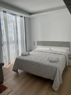a white bedroom with a large bed and large windows at Apartamento Castillo Deluxe in Sanlúcar de Barrameda