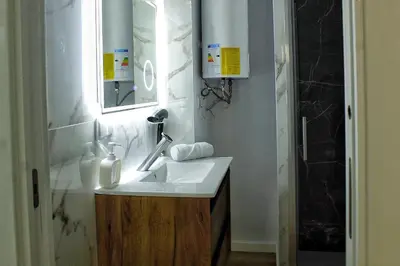 a bathroom with a sink and a mirror and a shower at Apartamento Castillo Deluxe in Sanlúcar de Barrameda
