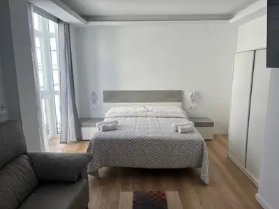 a white bedroom with a bed and a couch at Apartamento Castillo Deluxe in Sanlúcar de Barrameda