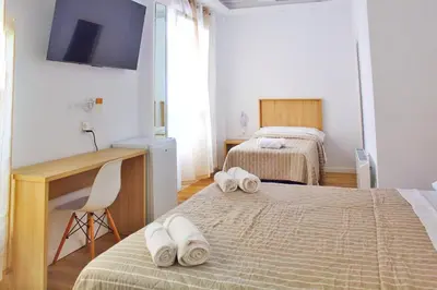 a bedroom with two beds and a desk with towels on them at Habitaciones Castillo Deluxe in Sanlúcar de Barrameda