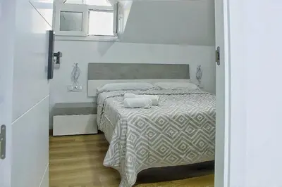 a bedroom with a bed with a white comforter and a window at Habitaciones Castillo Deluxe in Sanlúcar de Barrameda