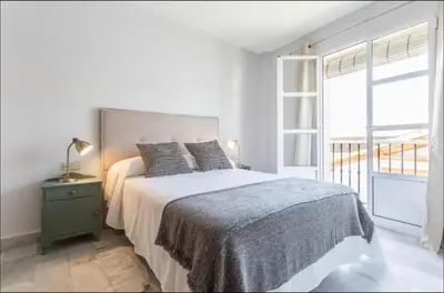 a white bedroom with a bed and a window at Luminoso y acogedor apartamento en el centro in El Puerto de Santa María